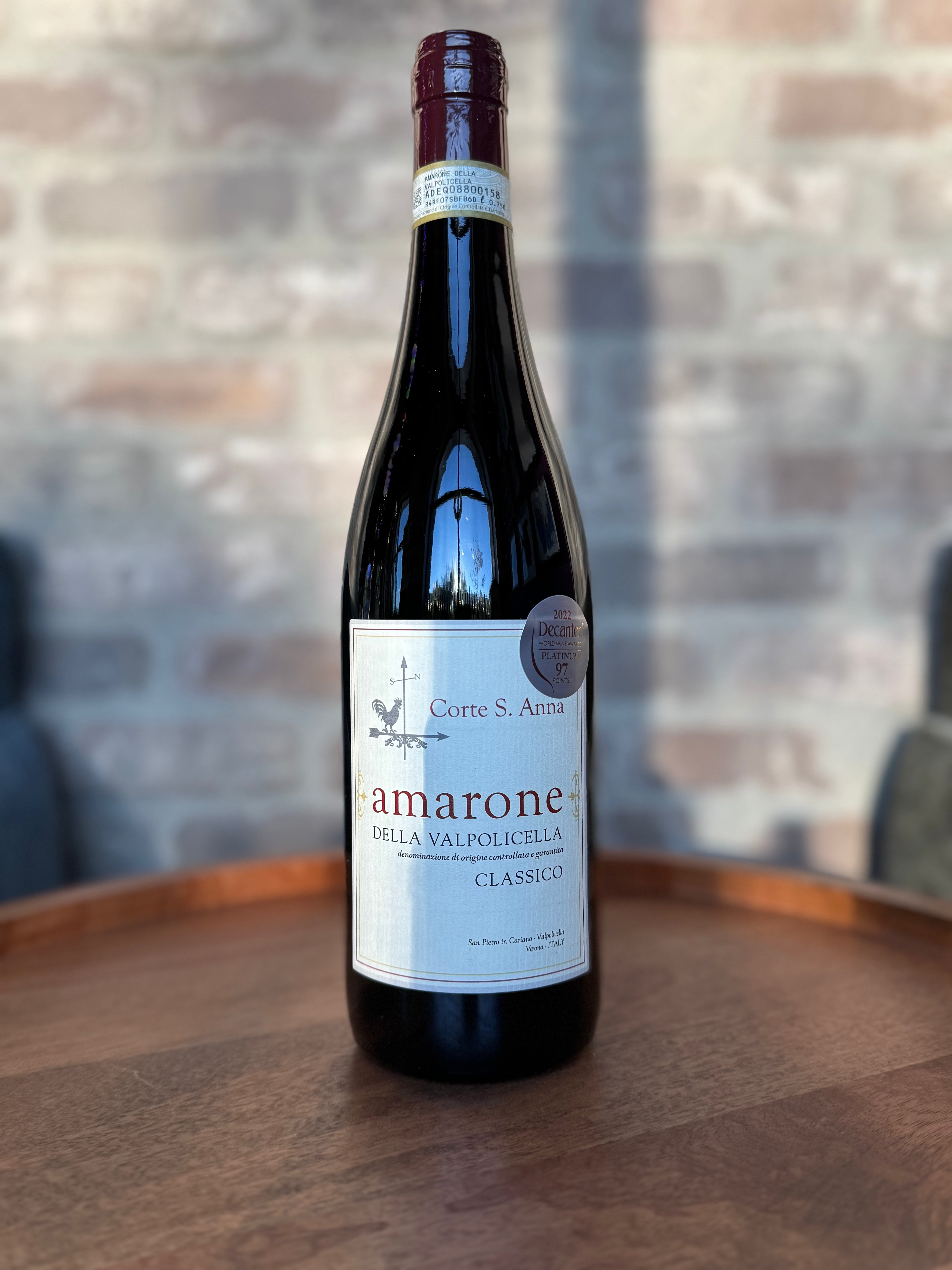 Wine bottle labeled 'amarone' on a wooden surface with a blurred brick wall background