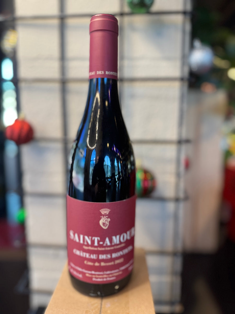 Wine bottle with 'Saint-Amour' label on a wooden surface with a blurred background