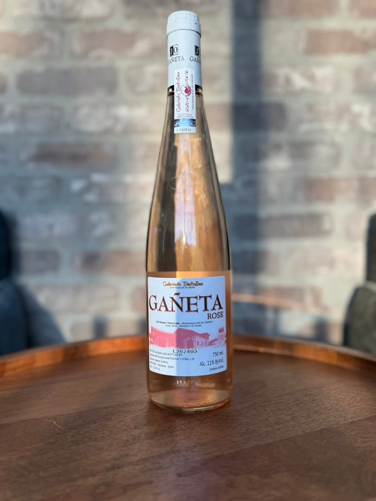 Bottle of Gáneta Rosé wine on a wooden surface with a blurred background