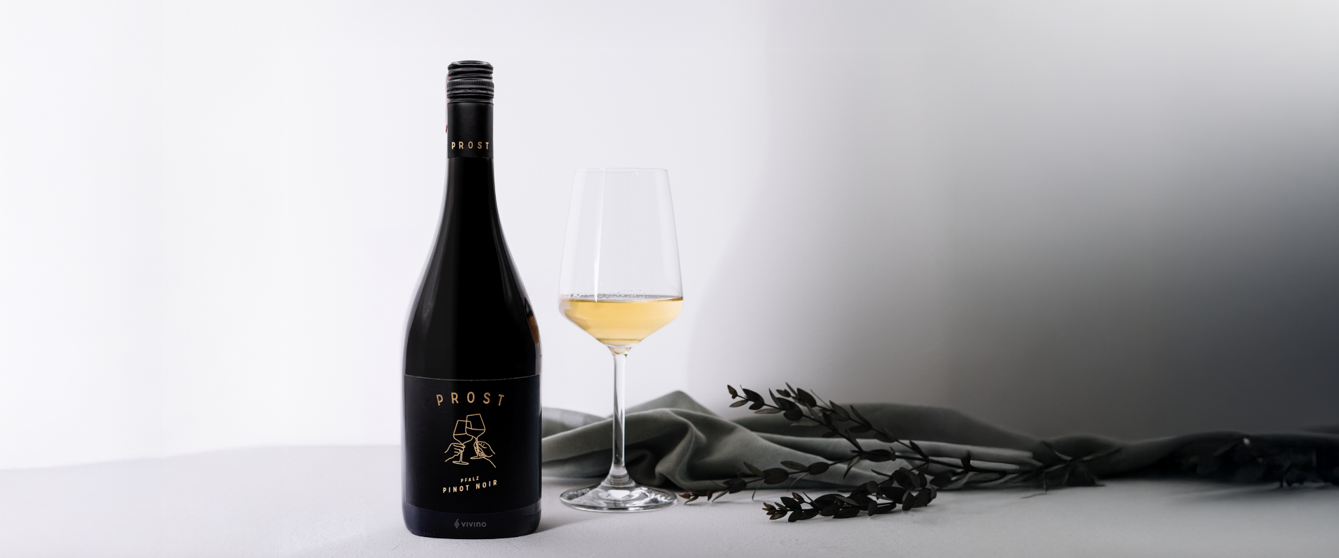 Wine bottle and glass on a white surface with a gray background