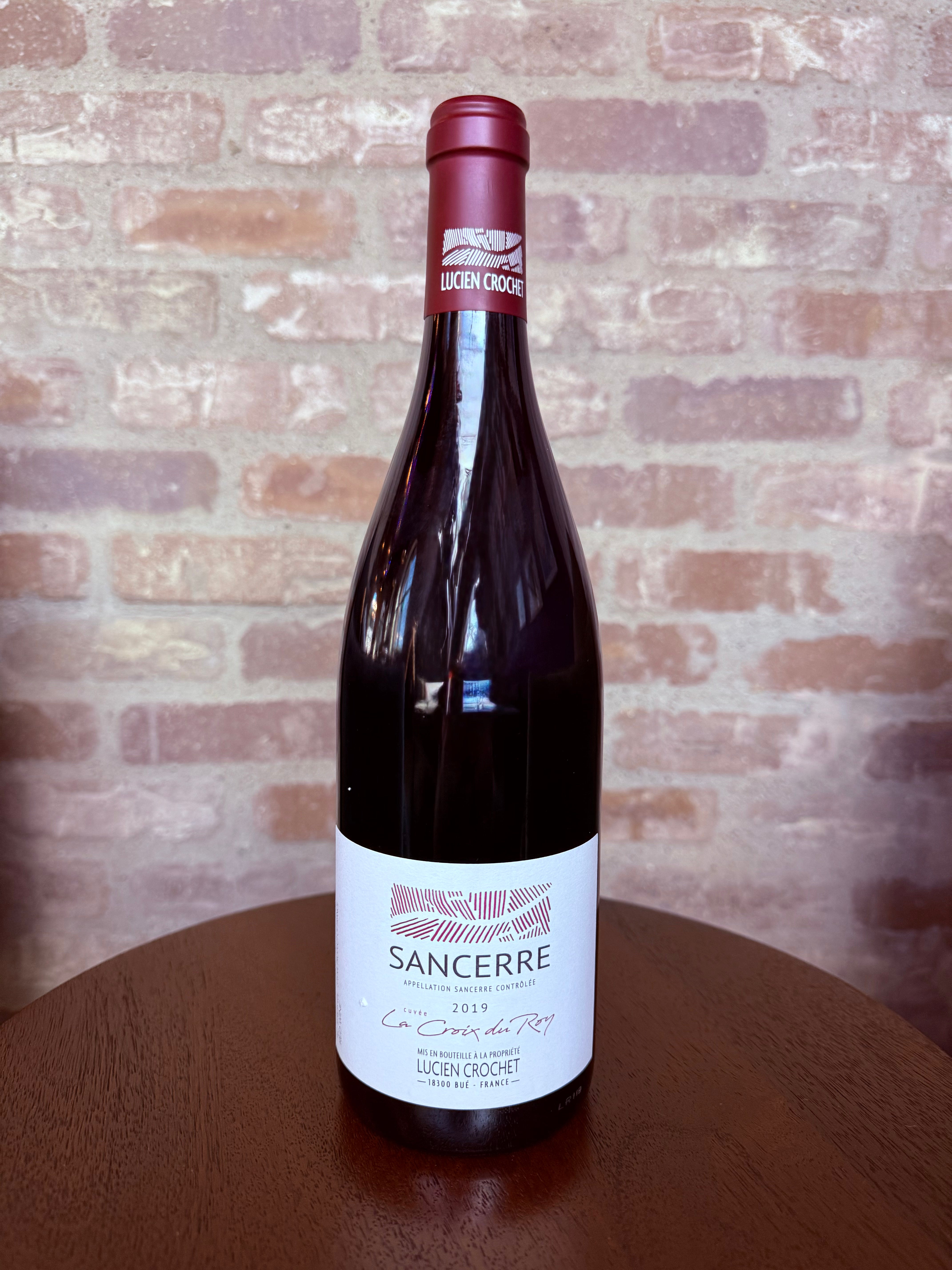 Wine bottle labeled 'Sancerre' on a wooden surface with a brick wall background