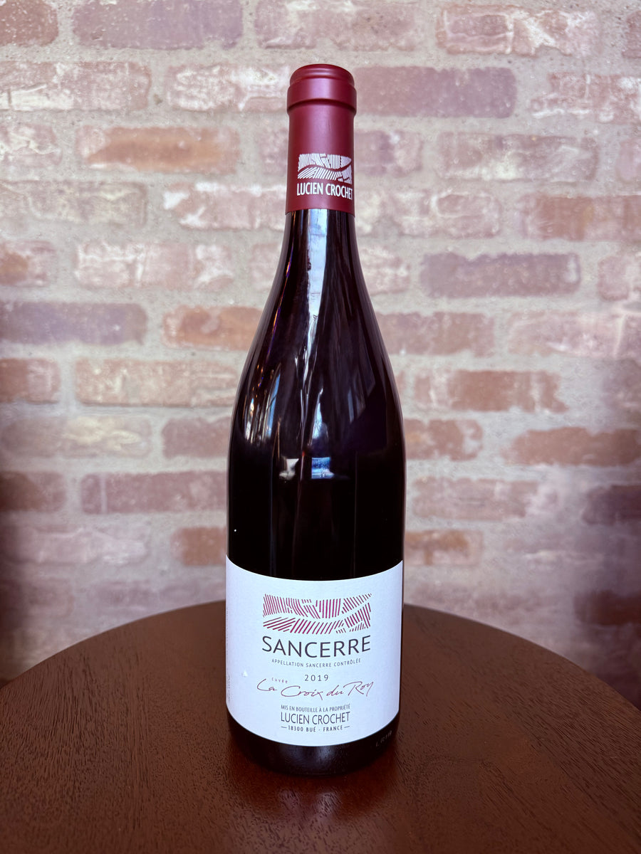 Wine bottle labeled 'Sancerre' on a wooden surface with a brick wall background