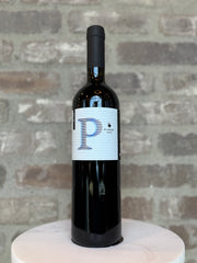 Wine bottle with a label featuring a large 'P' on a gray brick background