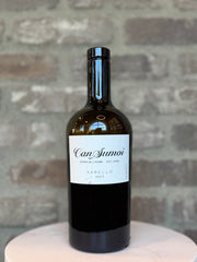 Wine bottle labeled 'Can Sumoi' on a stone surface with a stone wall background