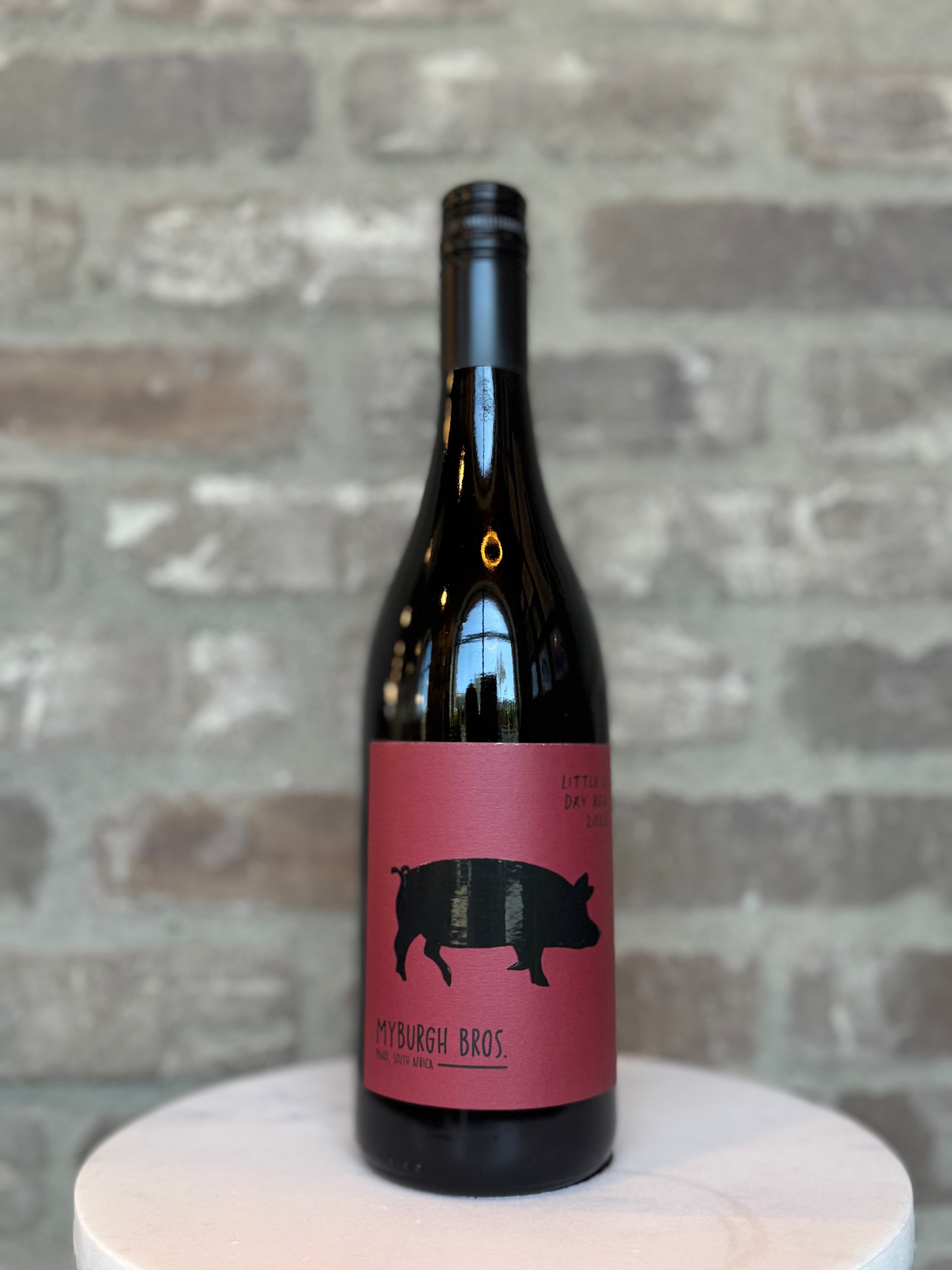 Wine bottle with a pink label featuring a black pig silhouette on a gray brick background