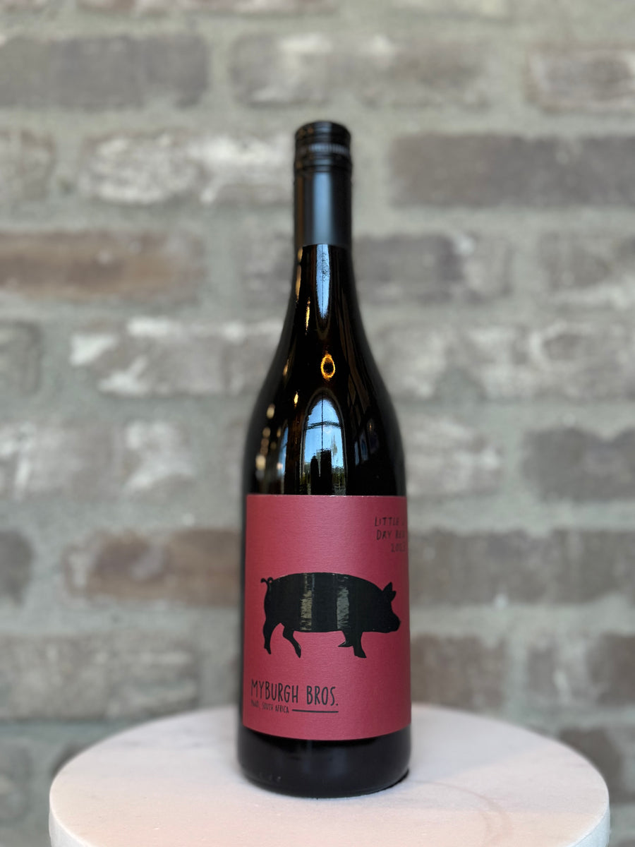 Wine bottle with a pink label featuring a black pig silhouette on a gray brick background