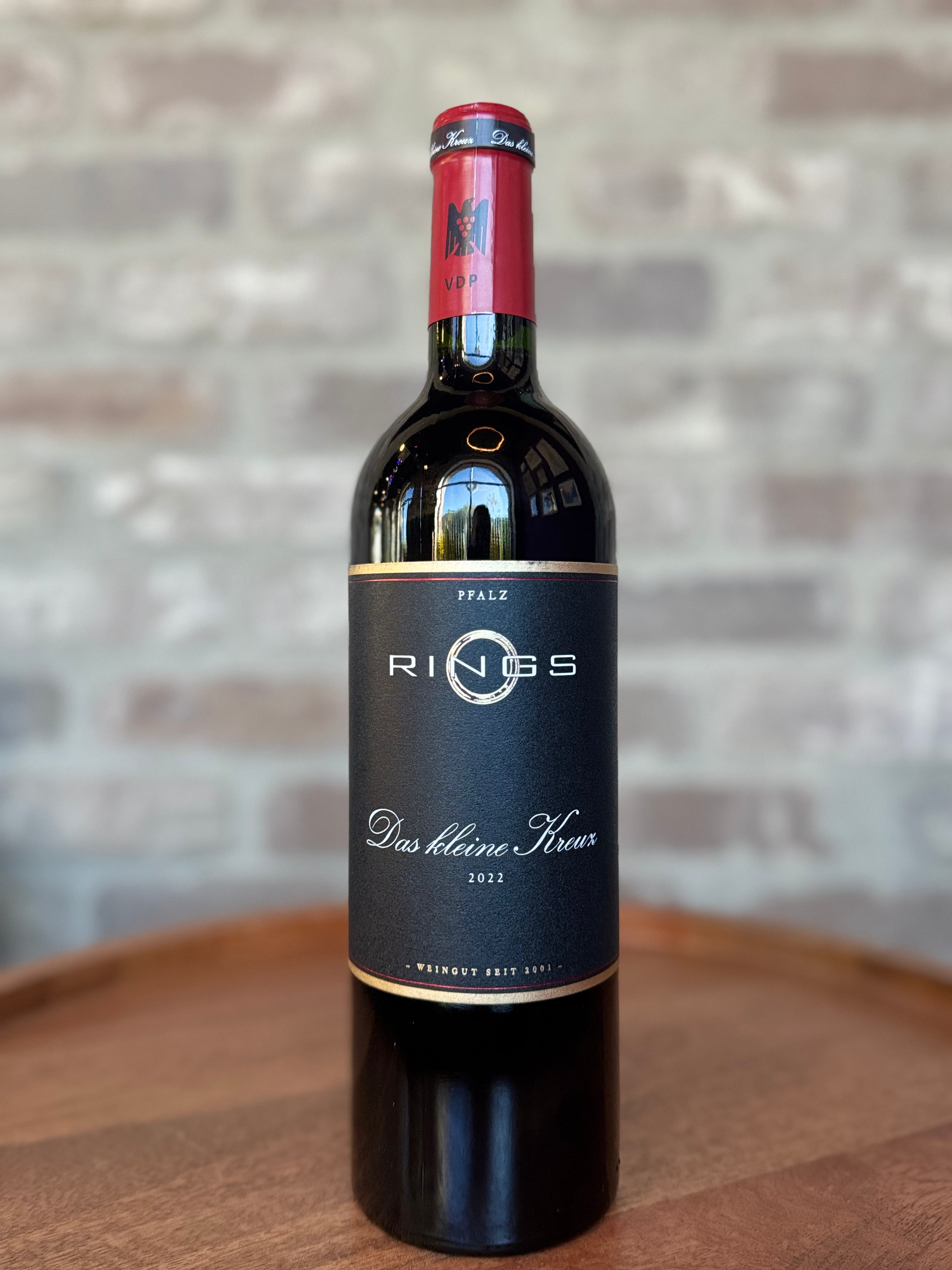 Wine bottle with 'Rings' label on a wooden surface and stone wall background