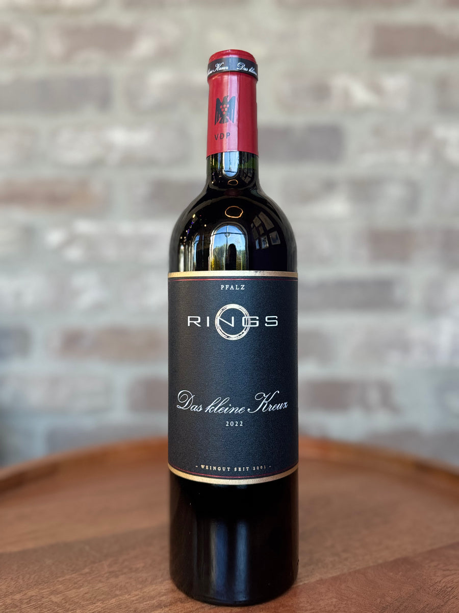 Wine bottle with 'Rings' label on a wooden surface and stone wall background