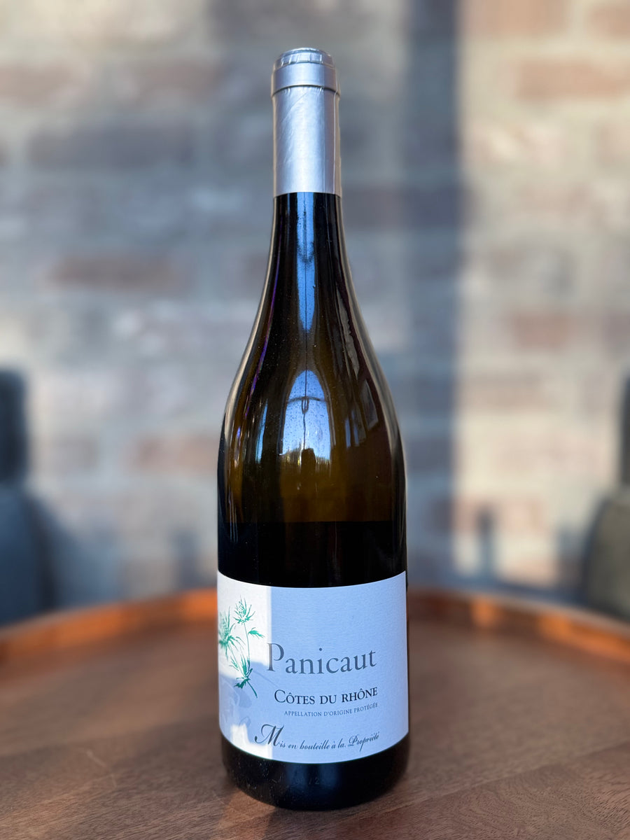 Wine bottle labeled 'Panicaut' on a wooden surface with a blurred background