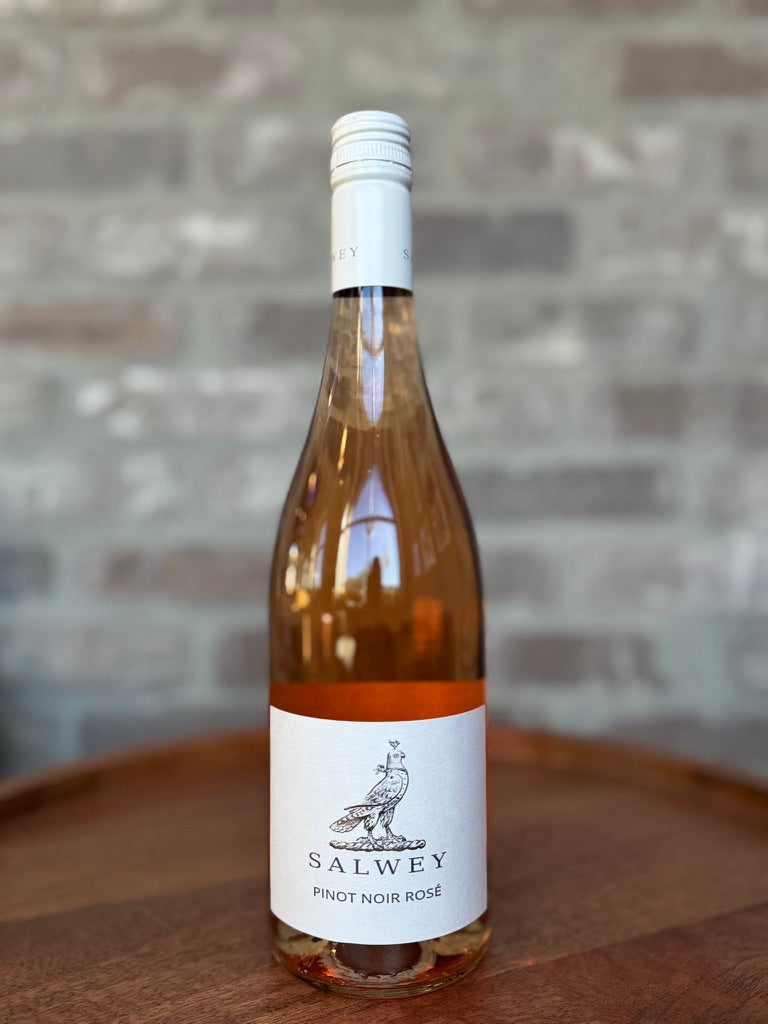 Bottle of Salwey Pinot Noir Rosé wine on a wooden surface with a stone wall background