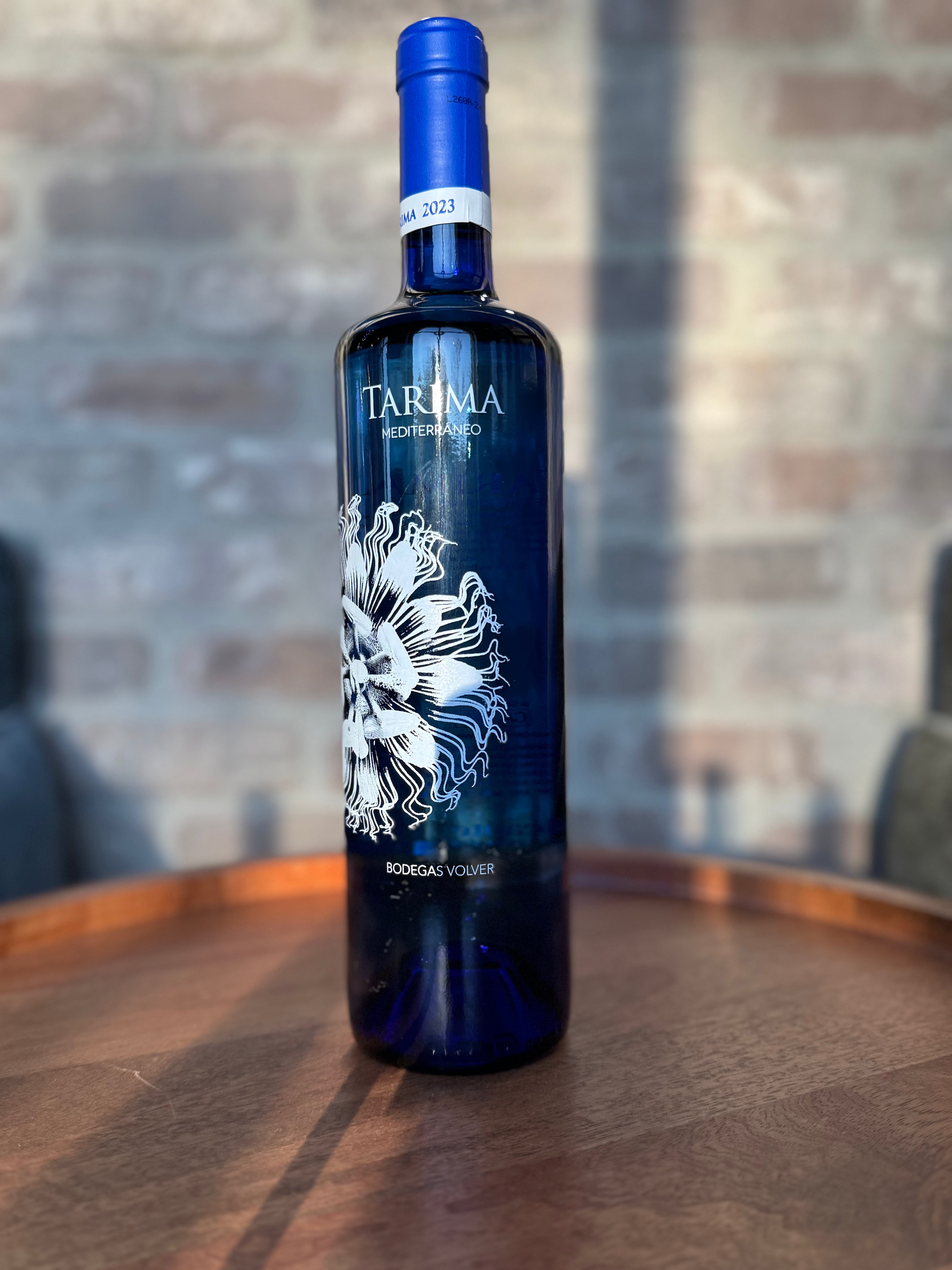 Blue wine bottle with white label on a wooden surface