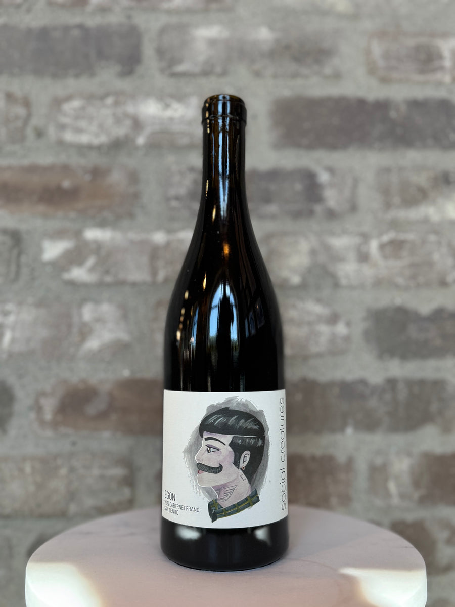 Wine bottle with a label featuring a portrait on a brick wall background