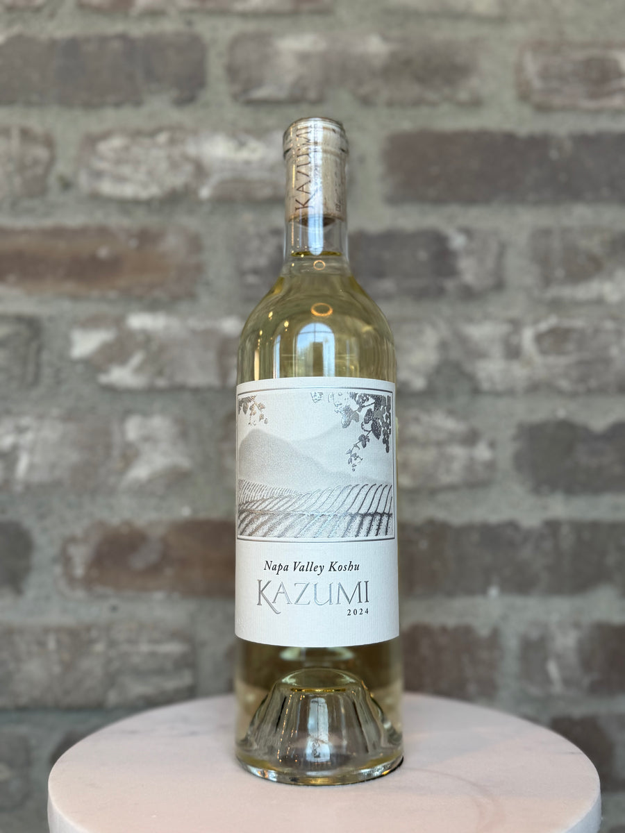Bottle of Kazumi Napa Valley Riesling on a wooden stand with a brick wall background
