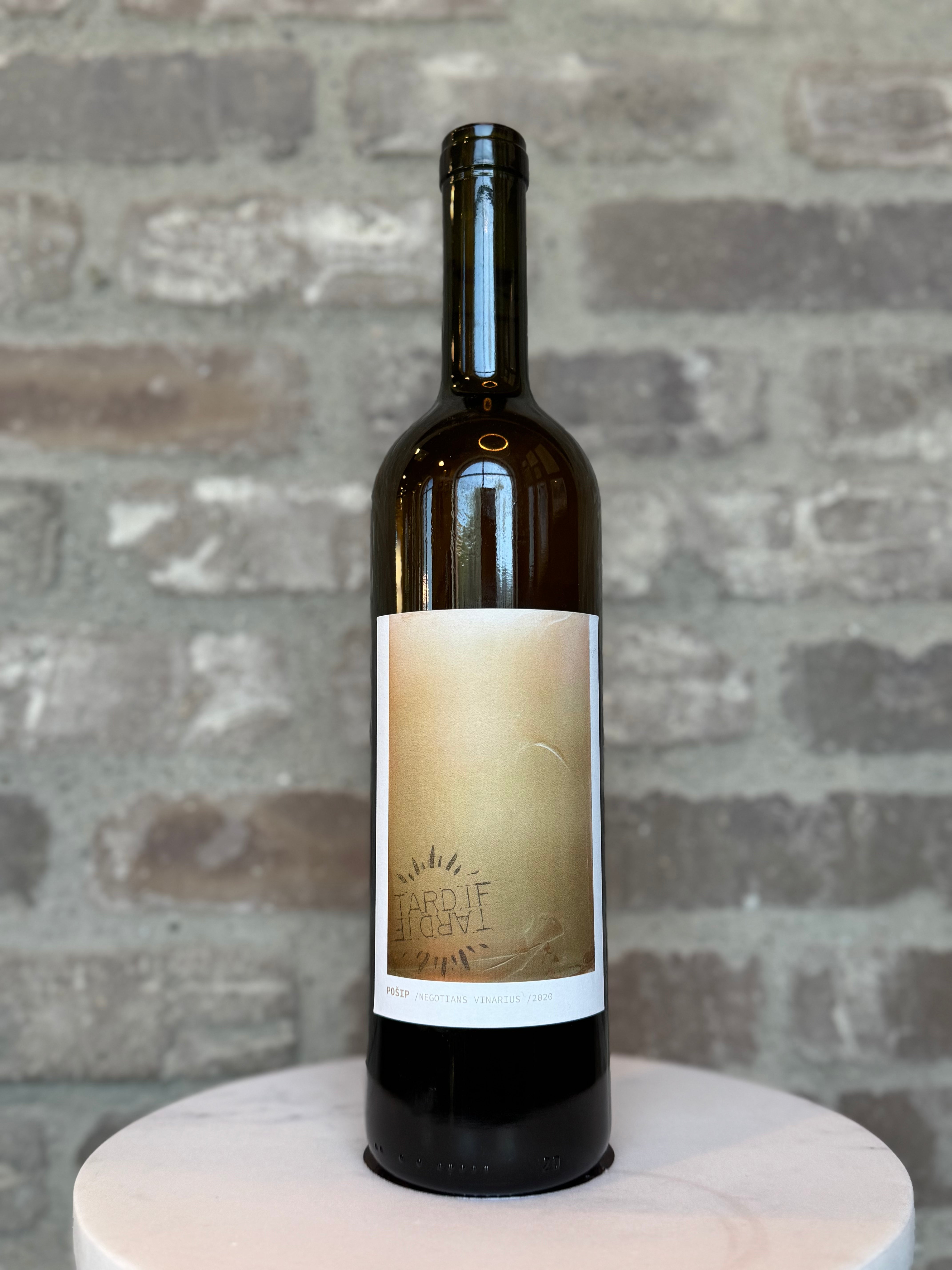 Wine bottle with a label on a round white platform against a stone wall background