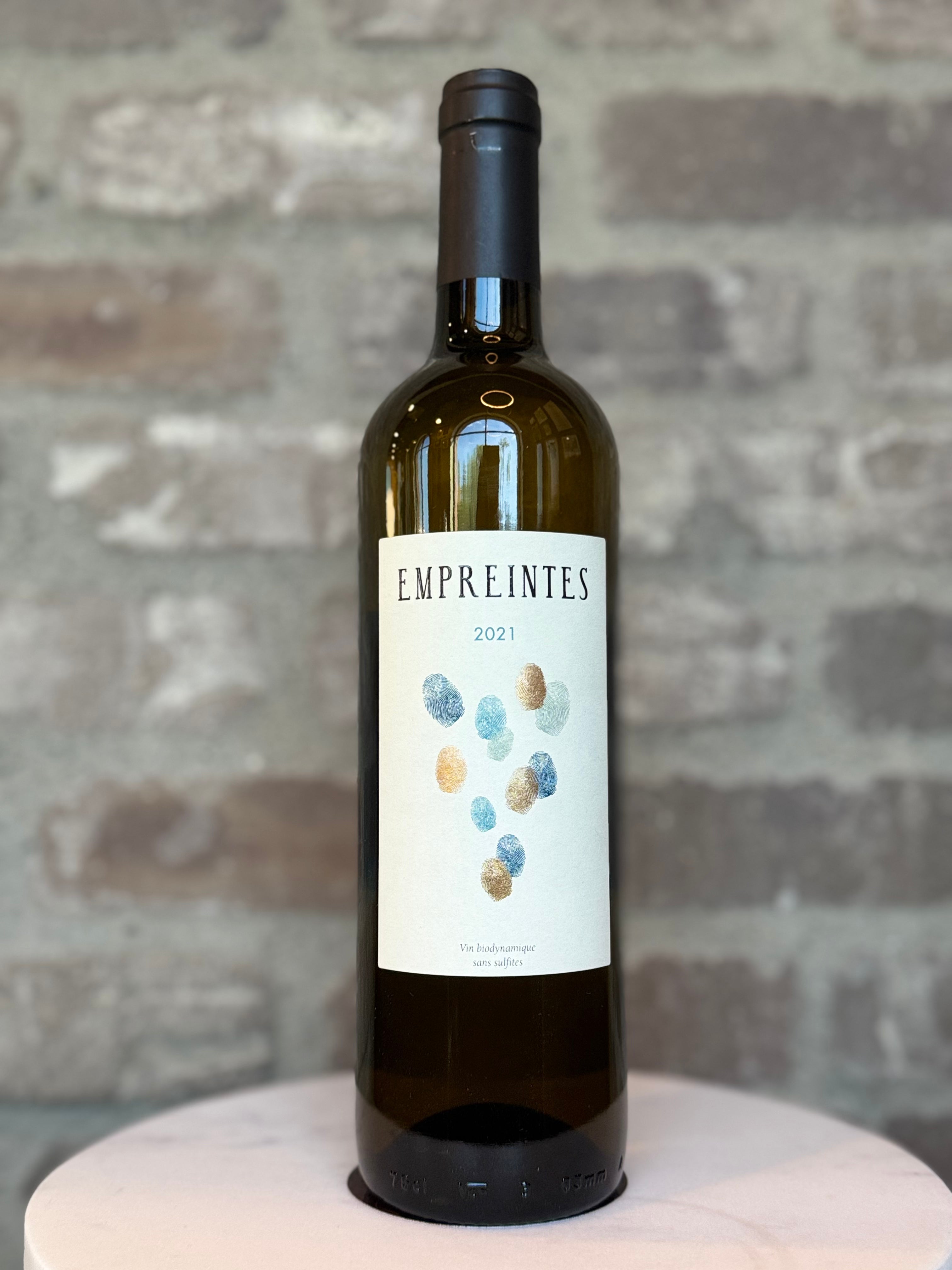 Wine bottle labeled 'Empreintes' on a textured surface with a brick wall background