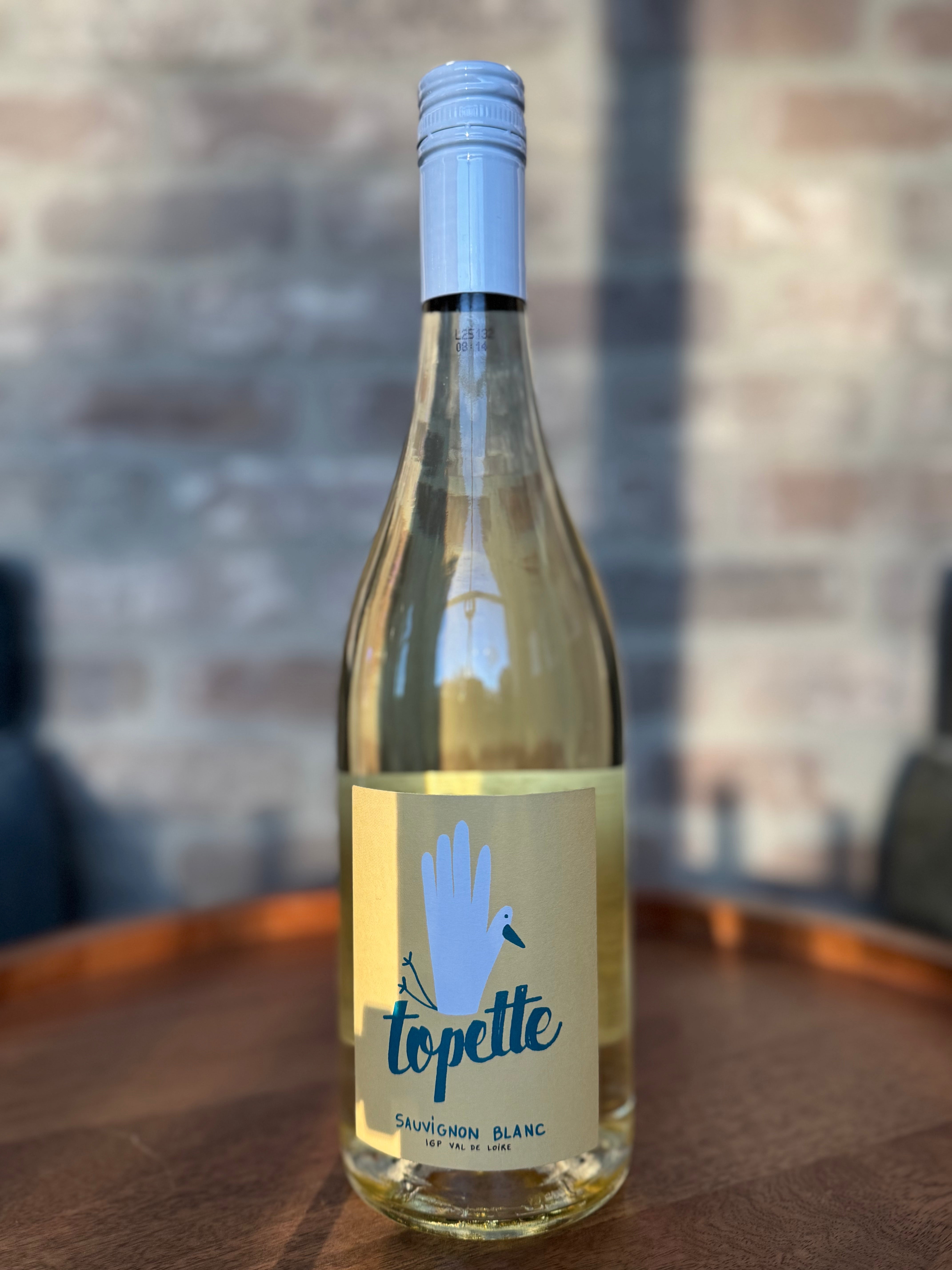 Bottle of topette Sauvignon Blanc wine on a wooden surface with a blurred background
