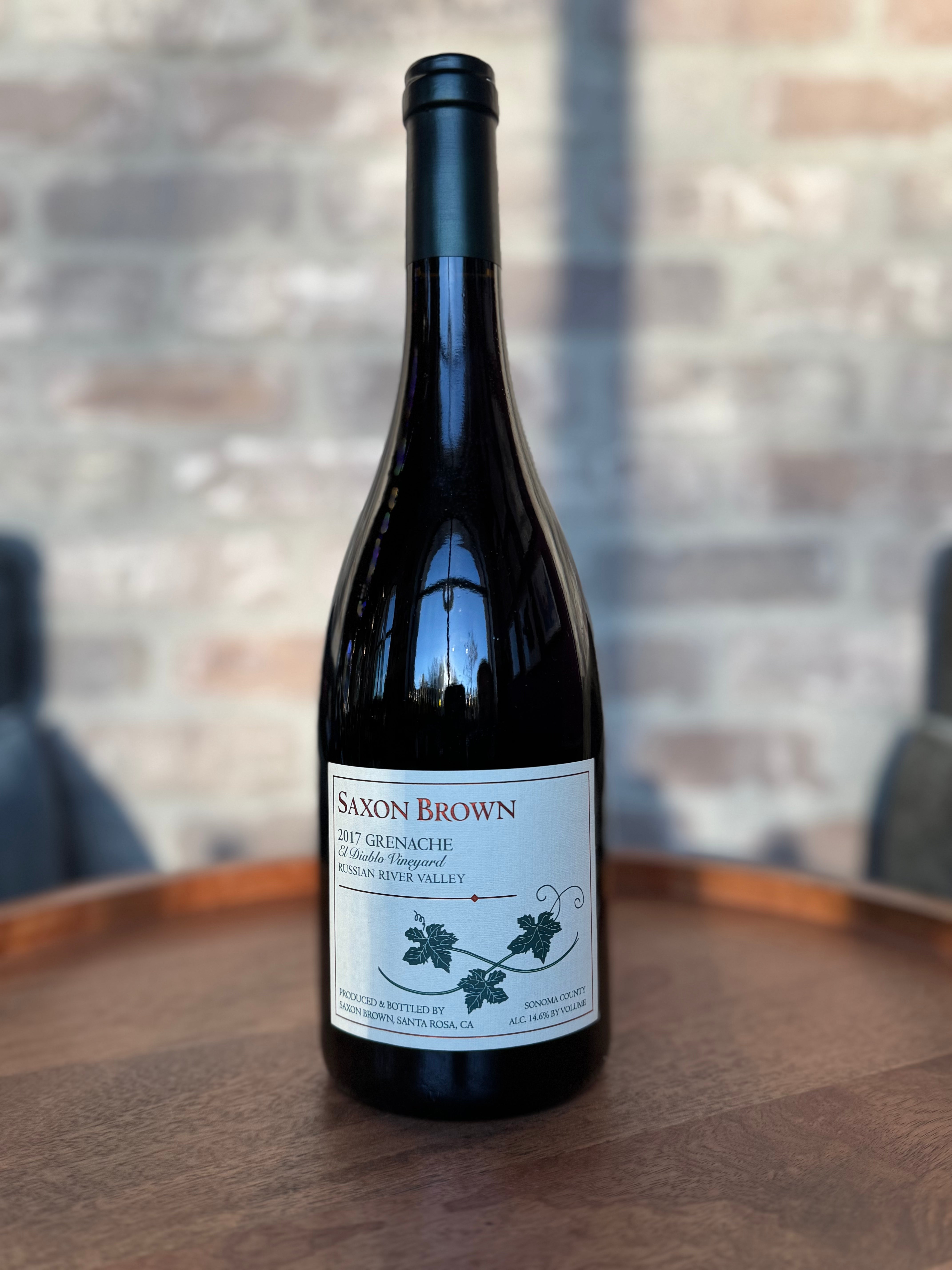 Wine bottle labeled 'Saxon Brown' on a wooden surface with a blurred background