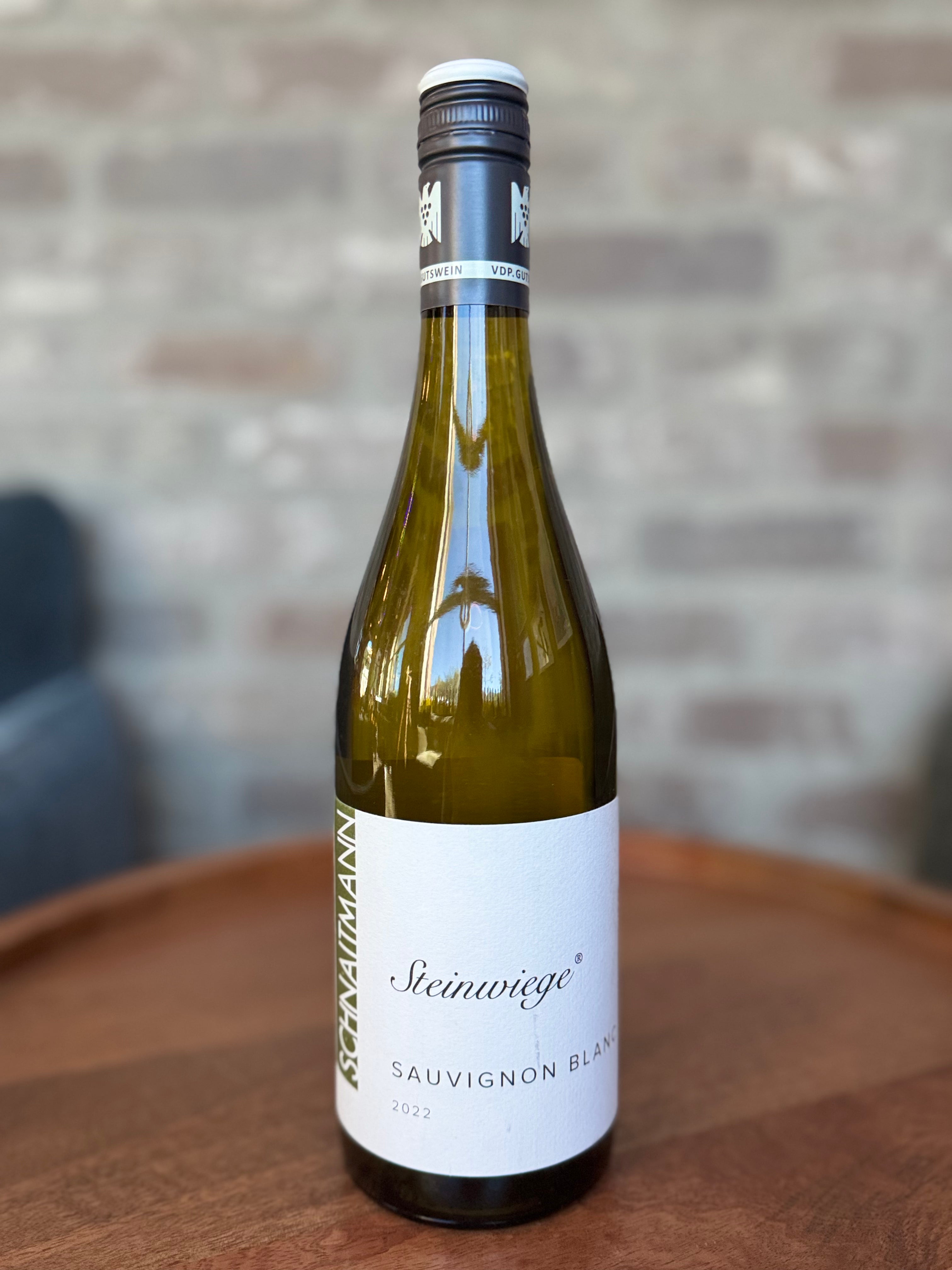 Wine bottle labeled 'Steinwäge' on a wooden surface with a blurred brick wall background