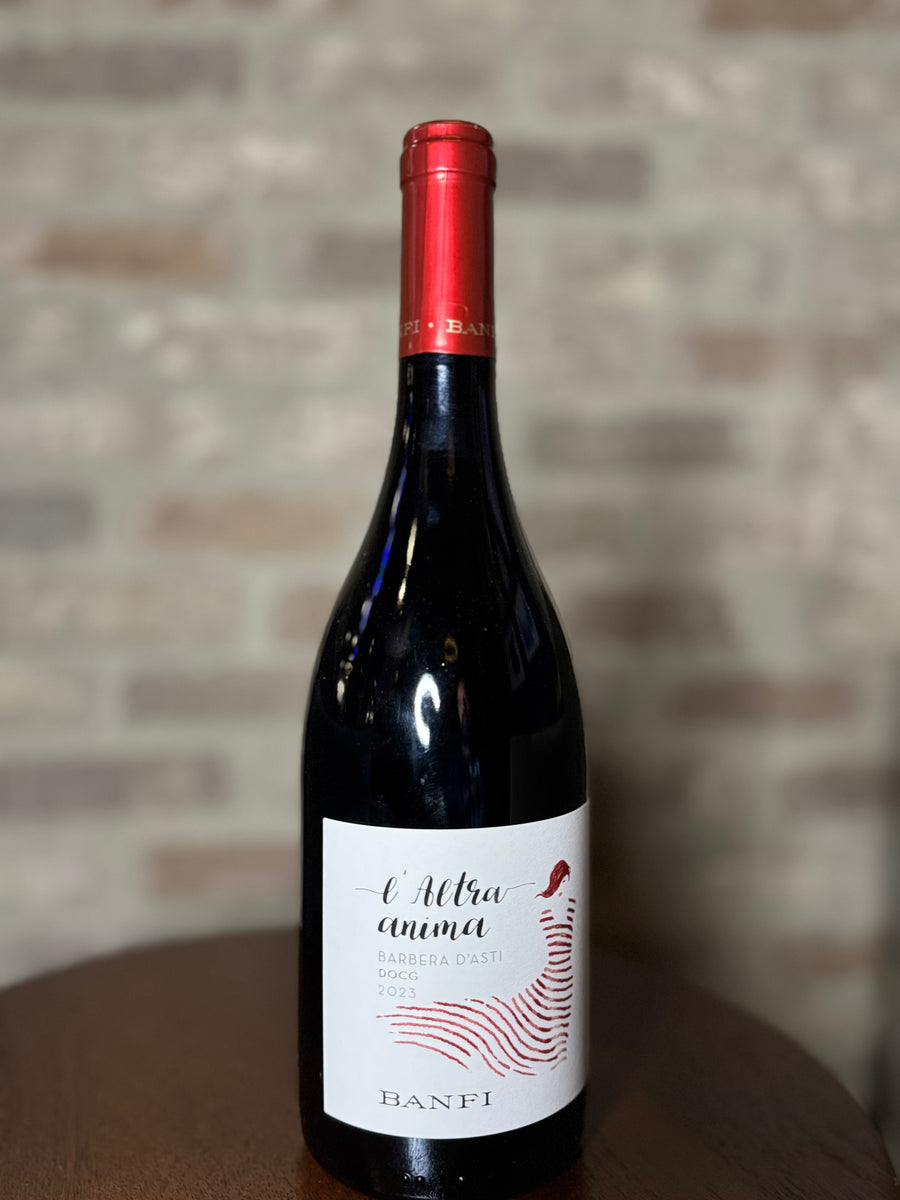 Wine bottle with red cap and white label on a wooden surface with a brick wall background