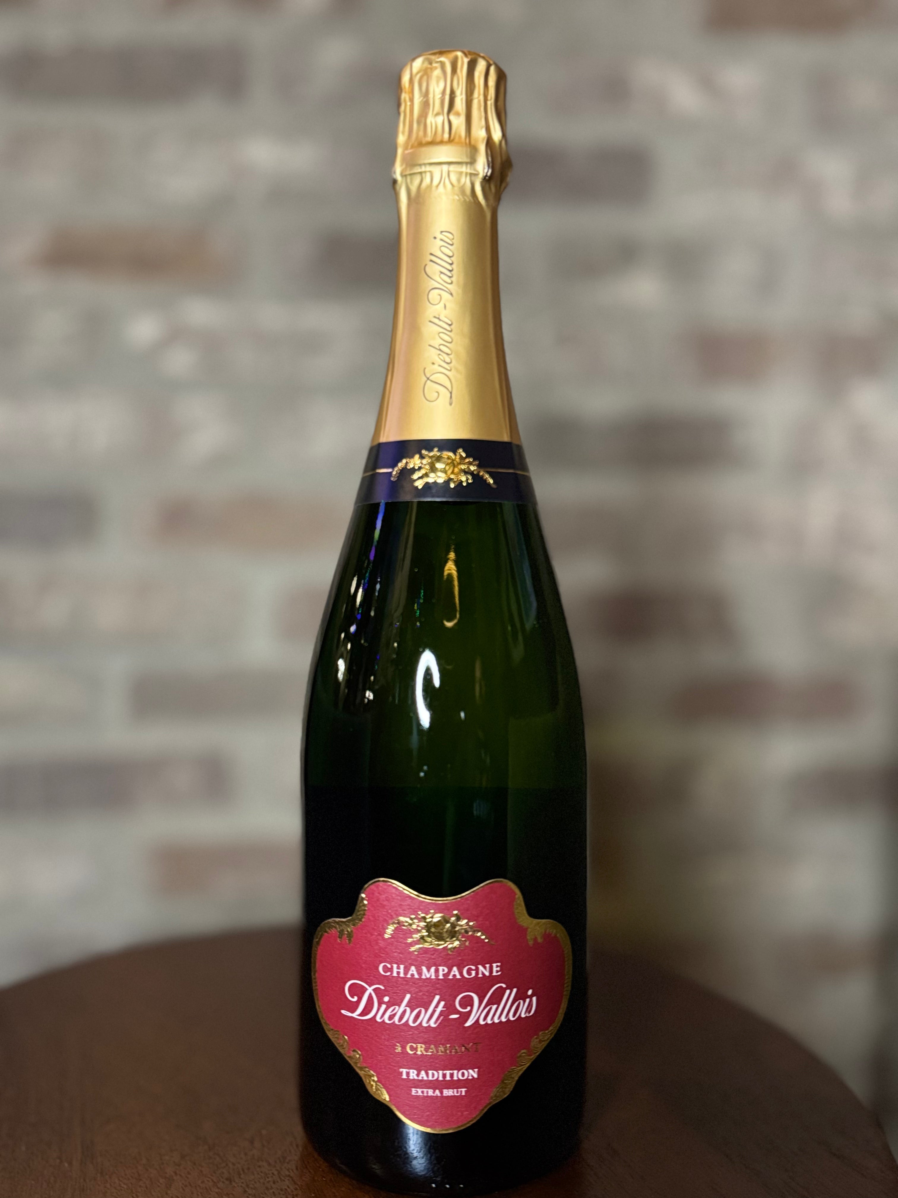 Bottle of Diebolt Vallois champagne with a gold foil cap on a wooden surface.