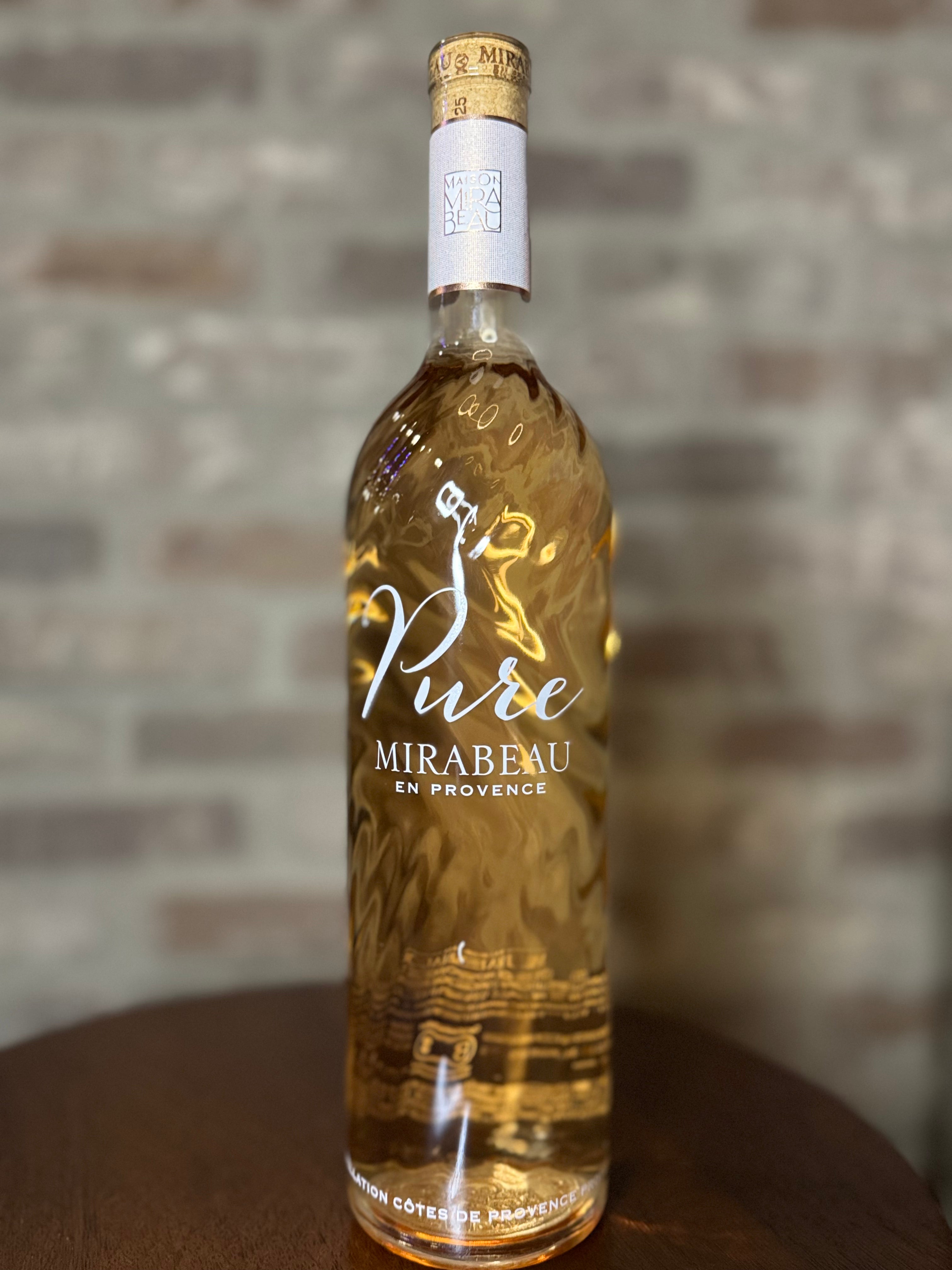 Bottle of Mirabeau Pure wine on a wooden surface with a brick wall background