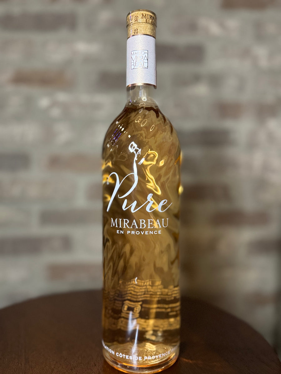 Bottle of Mirabeau Pure wine on a wooden surface with a brick wall background