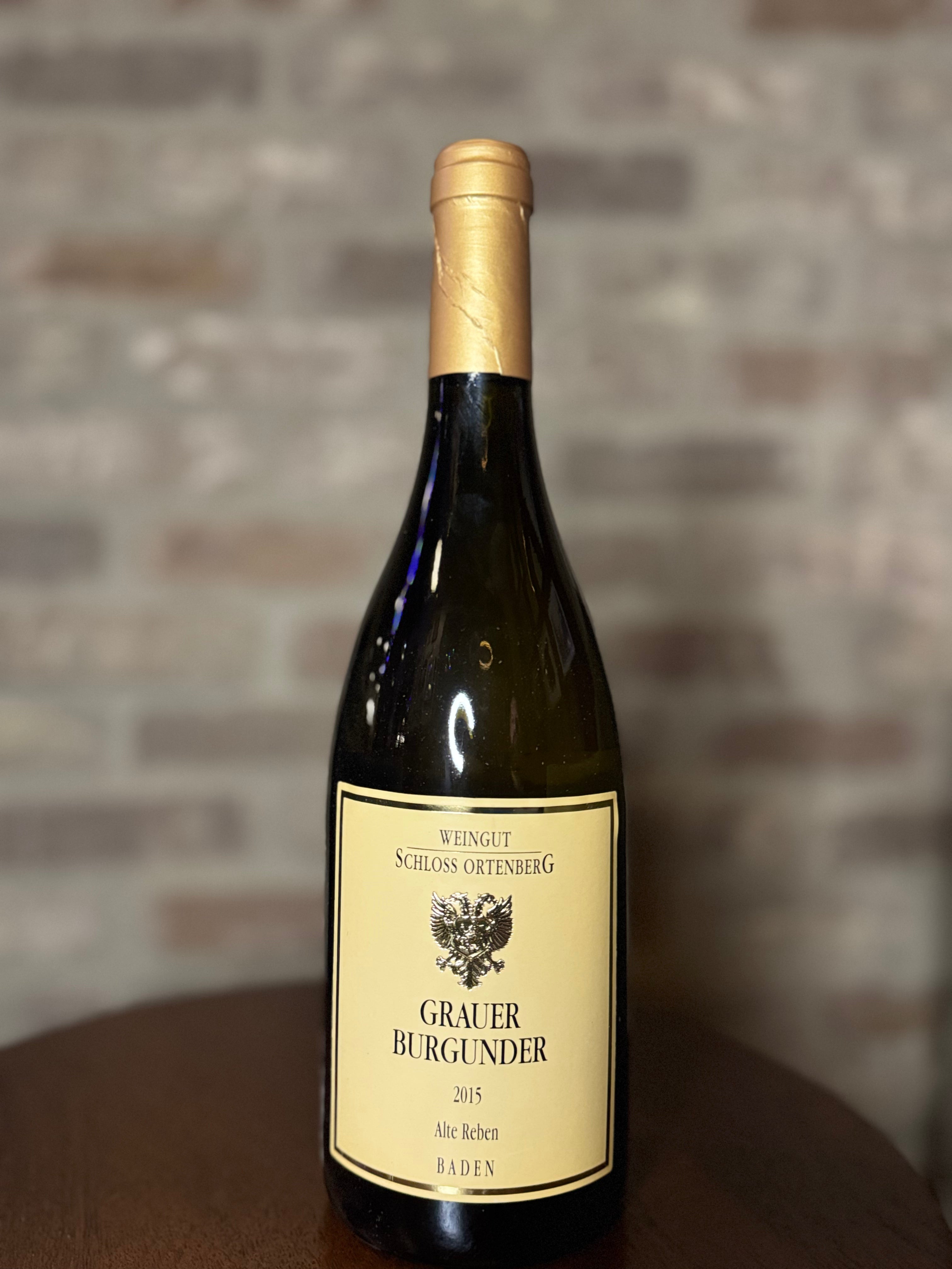 Wine bottle with a gold label on a wooden surface against a brick wall background