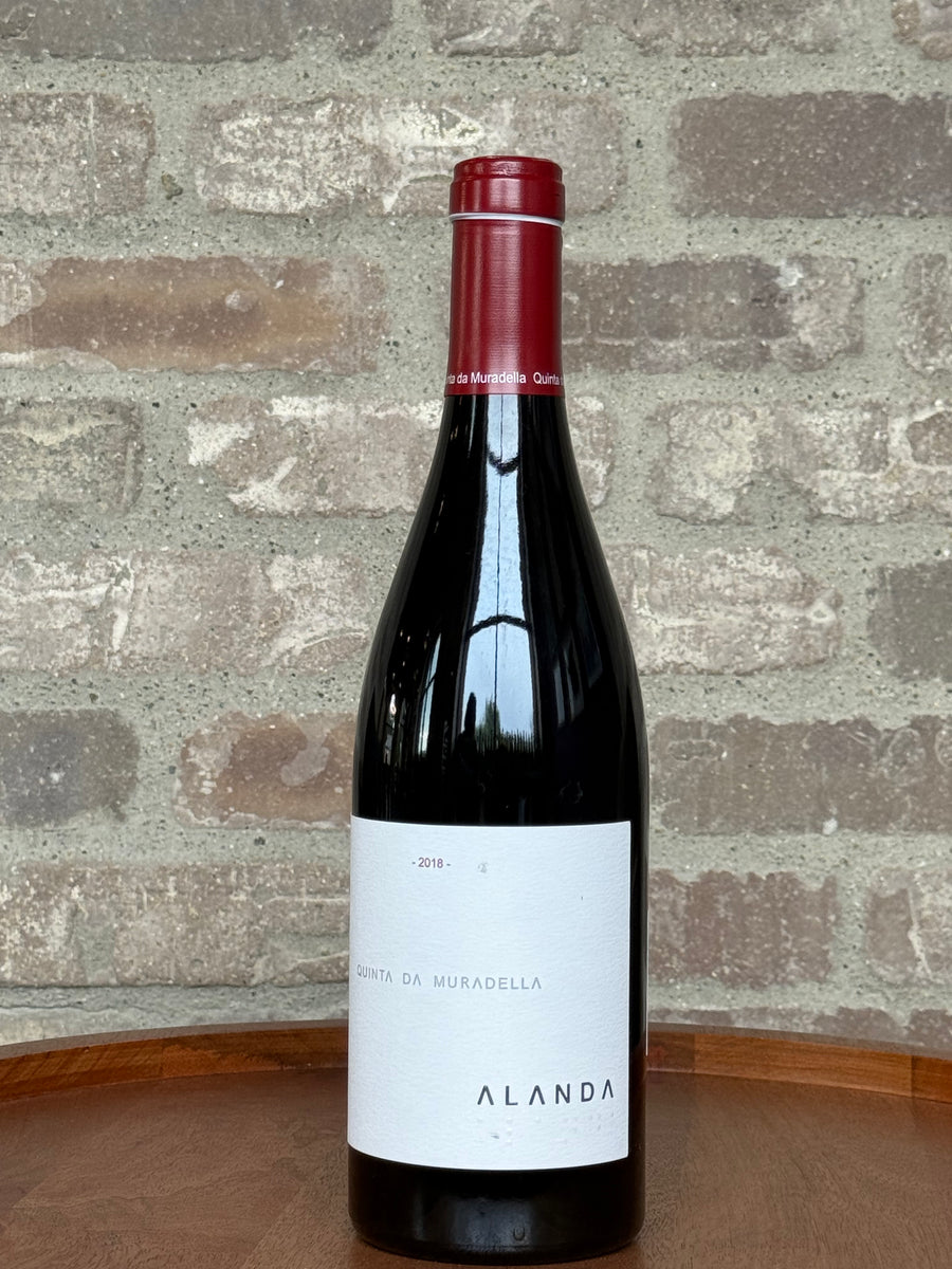 Wine bottle with a red label and white label on a stone surface and stone wall background