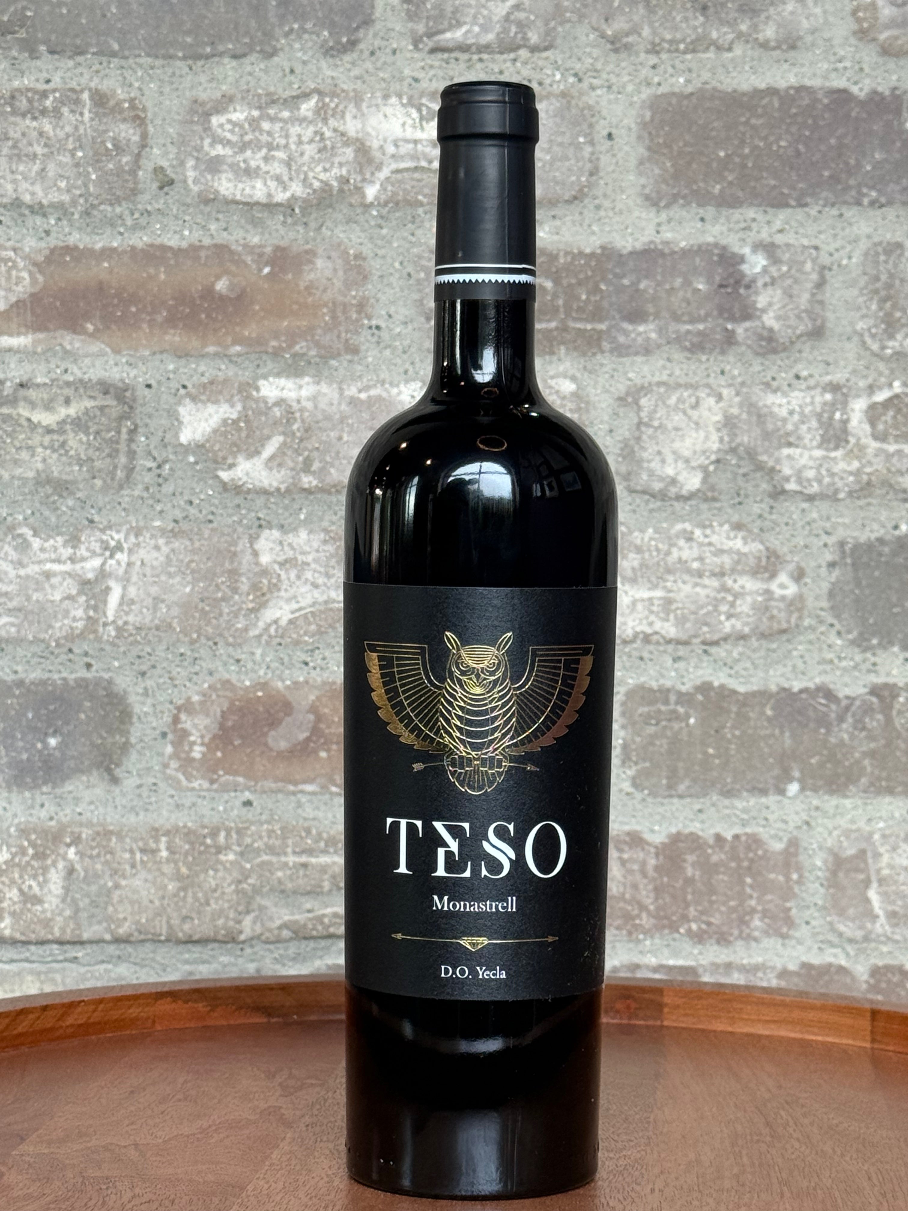 Wine bottle labeled 'TESO' against a textured stone wall background