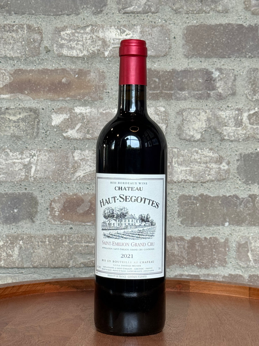 Bottle of Chateau Haut-Segottes 2021 wine against a stone wall background