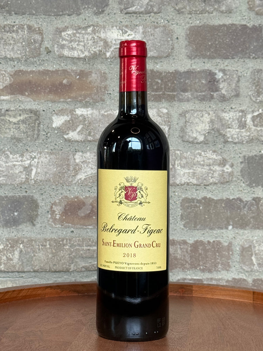 Bottle of Chateau Belregard Figeac wine against a stone wall background