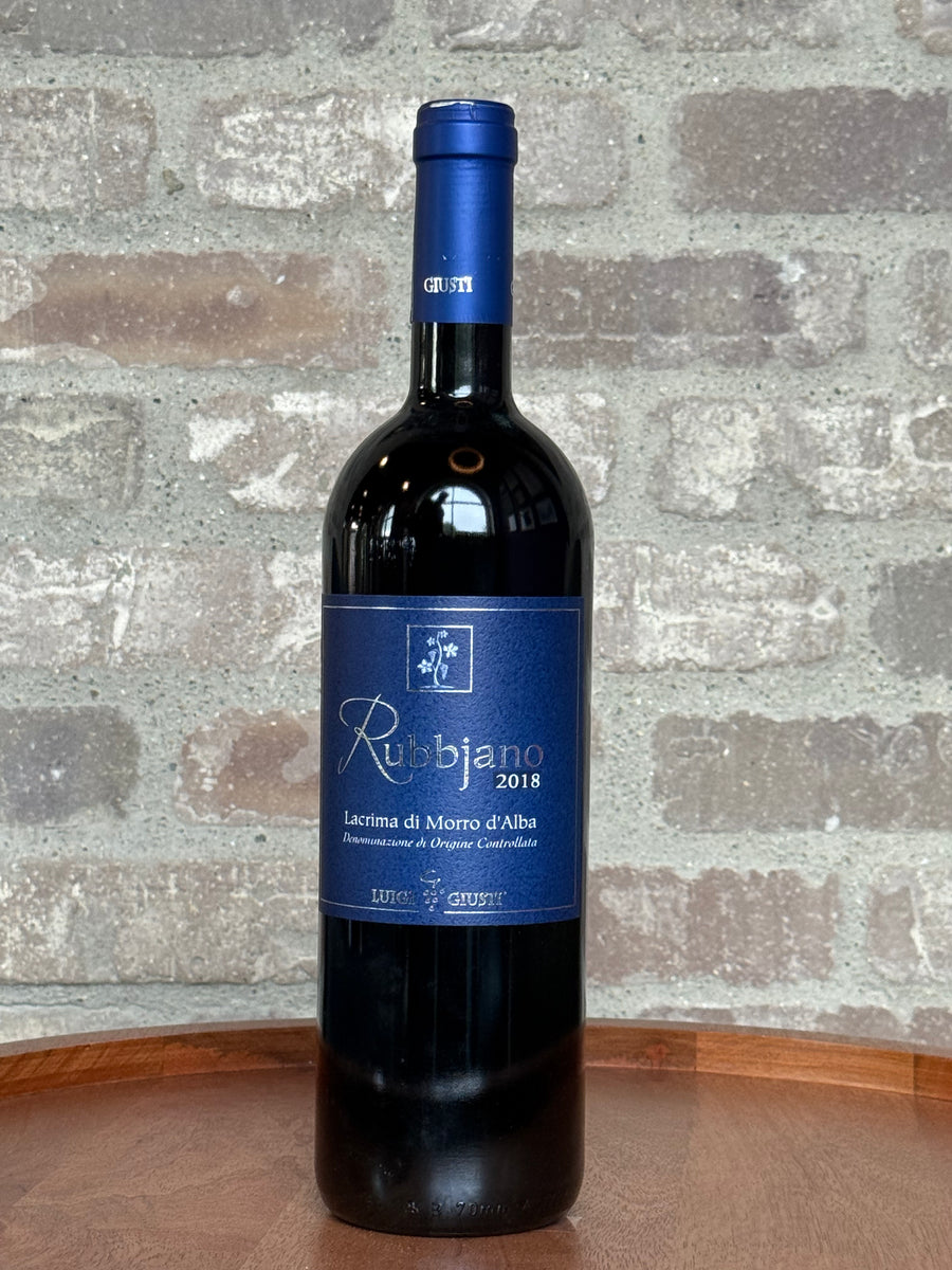 Wine bottle with blue label on a wooden surface and stone wall background