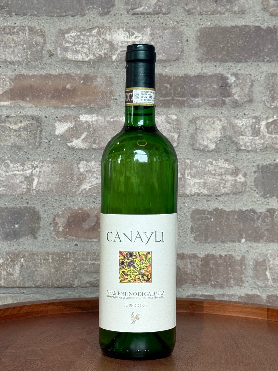 Green wine bottle with 'Canayli' label on a stone surface and stone wall background