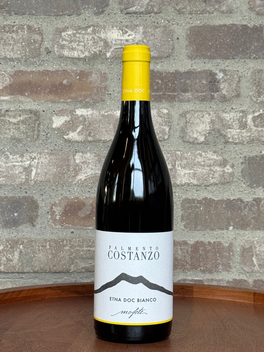 Bottle of Palmento Costanzo wine against a stone wall background