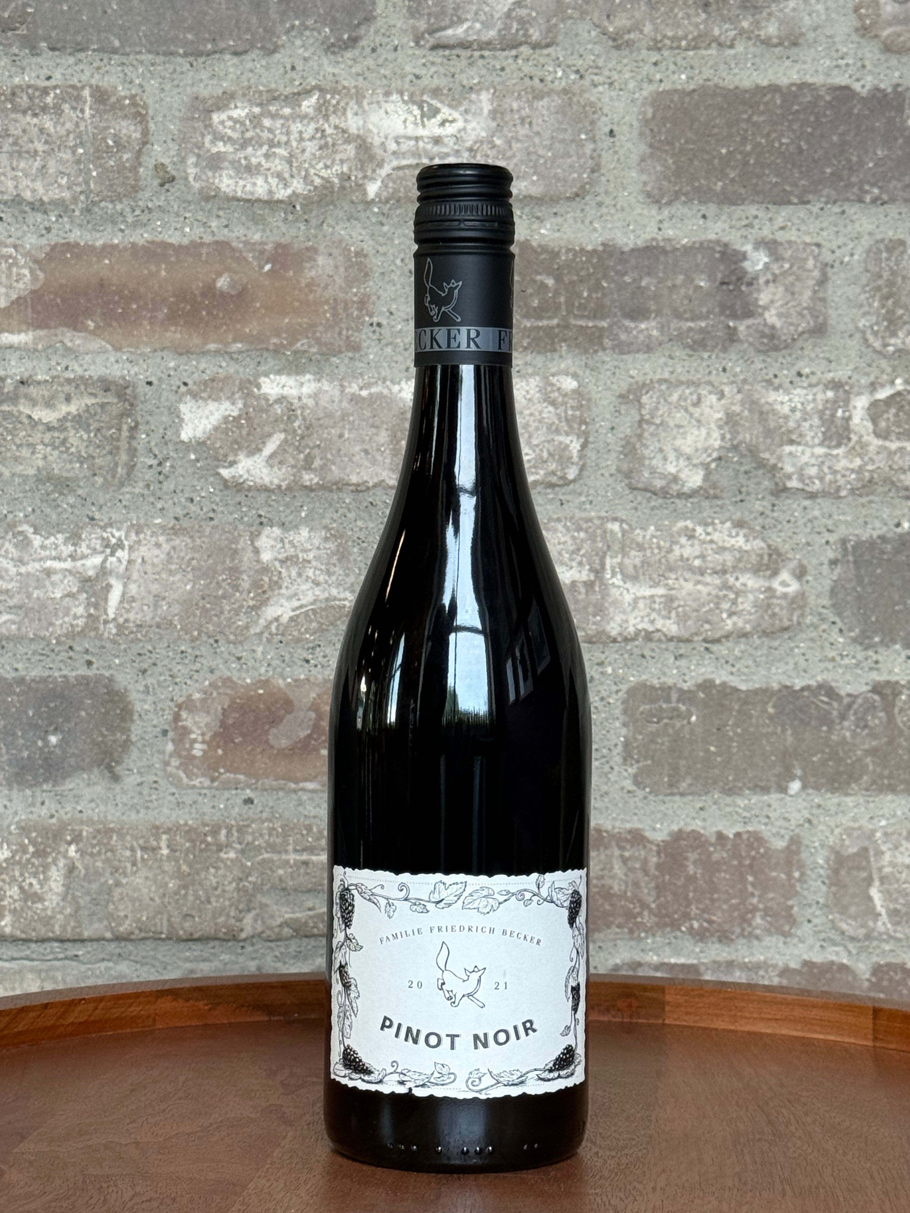 Wine bottle labeled 'Pinot Noir' on a wooden surface with a stone wall background