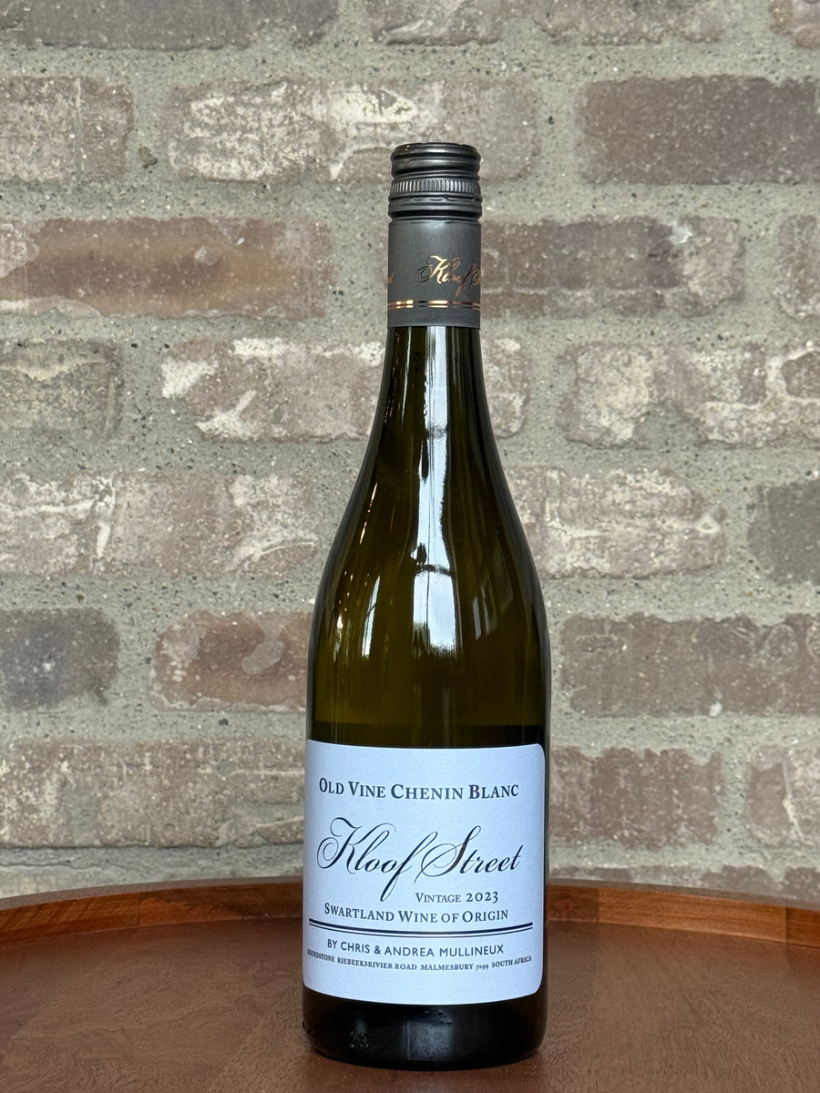 Bottle of Old Vine Chenin Blanc wine on a wooden surface with a stone wall background