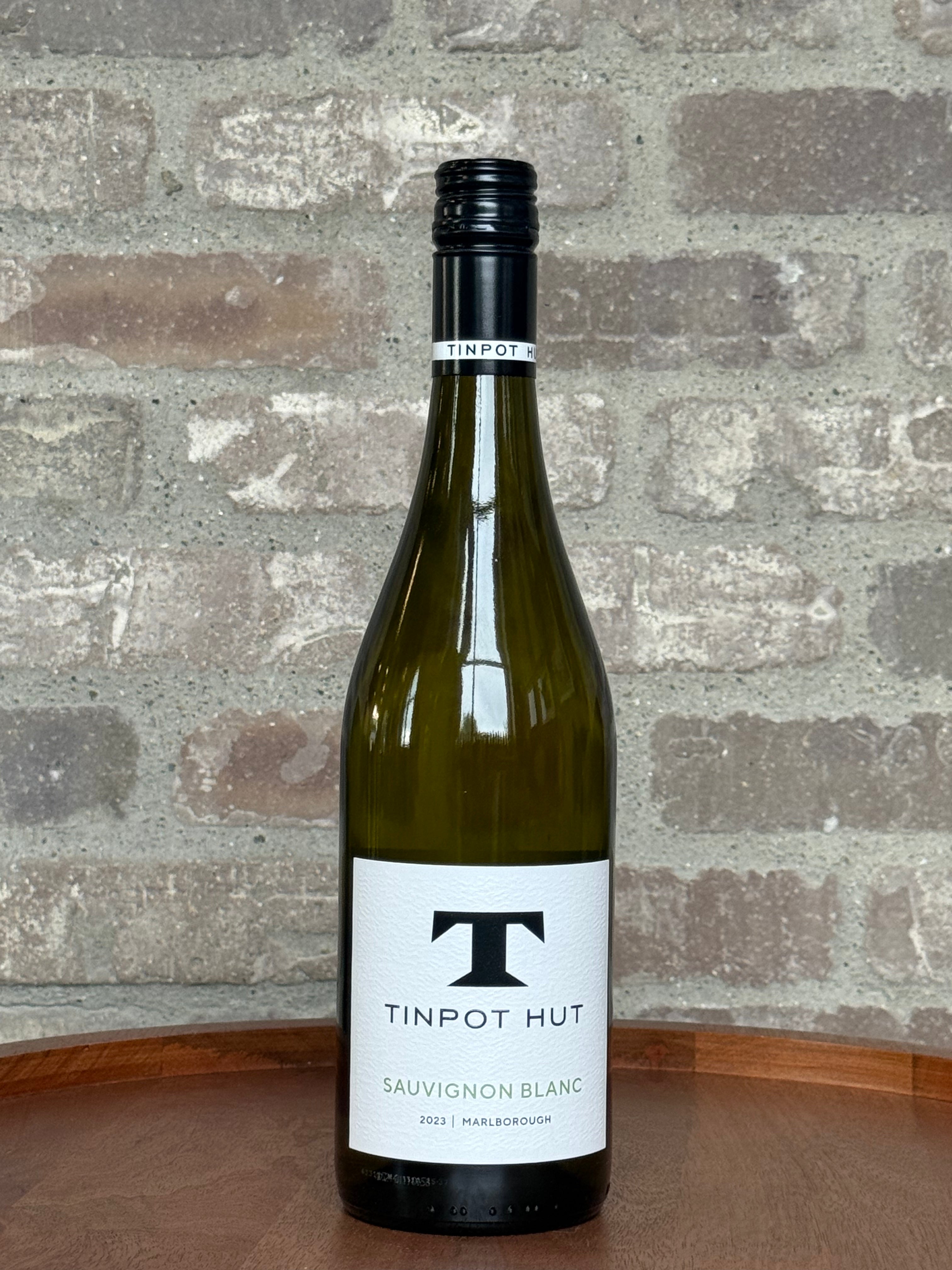 Bottle of Tinpot Hut Sauvignon Blanc wine against a stone wall background
