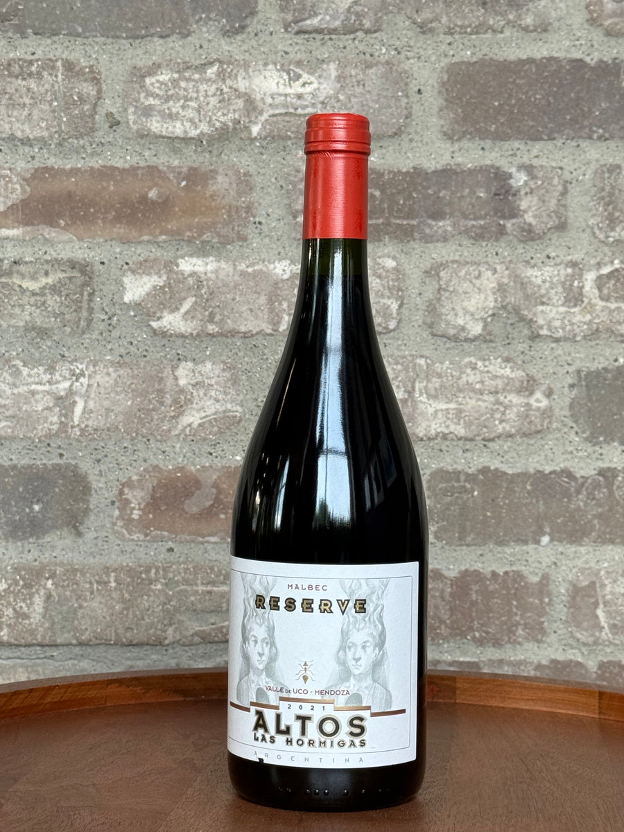 Wine bottle with red cap and white label against a brick wall background