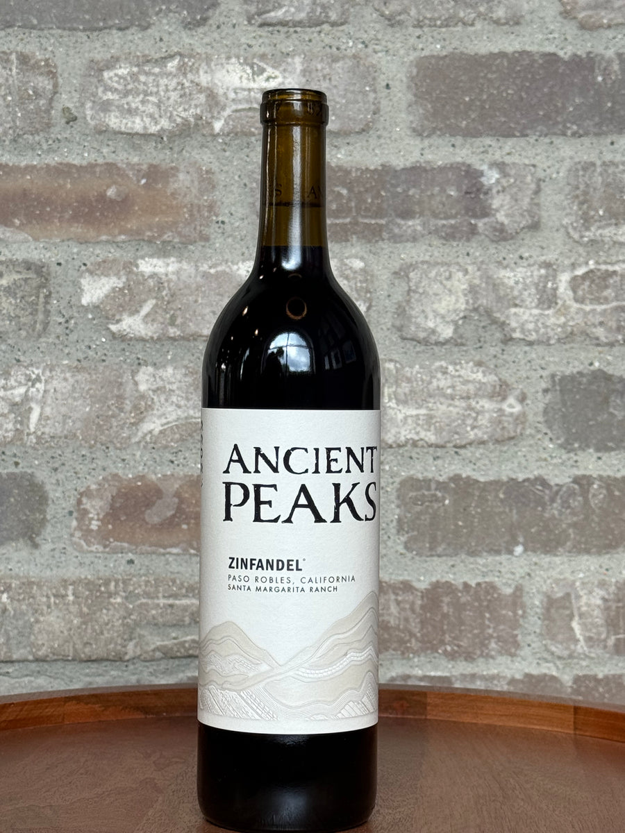 Bottle of Ancient Peaks Zinfandel wine against a textured stone wall background