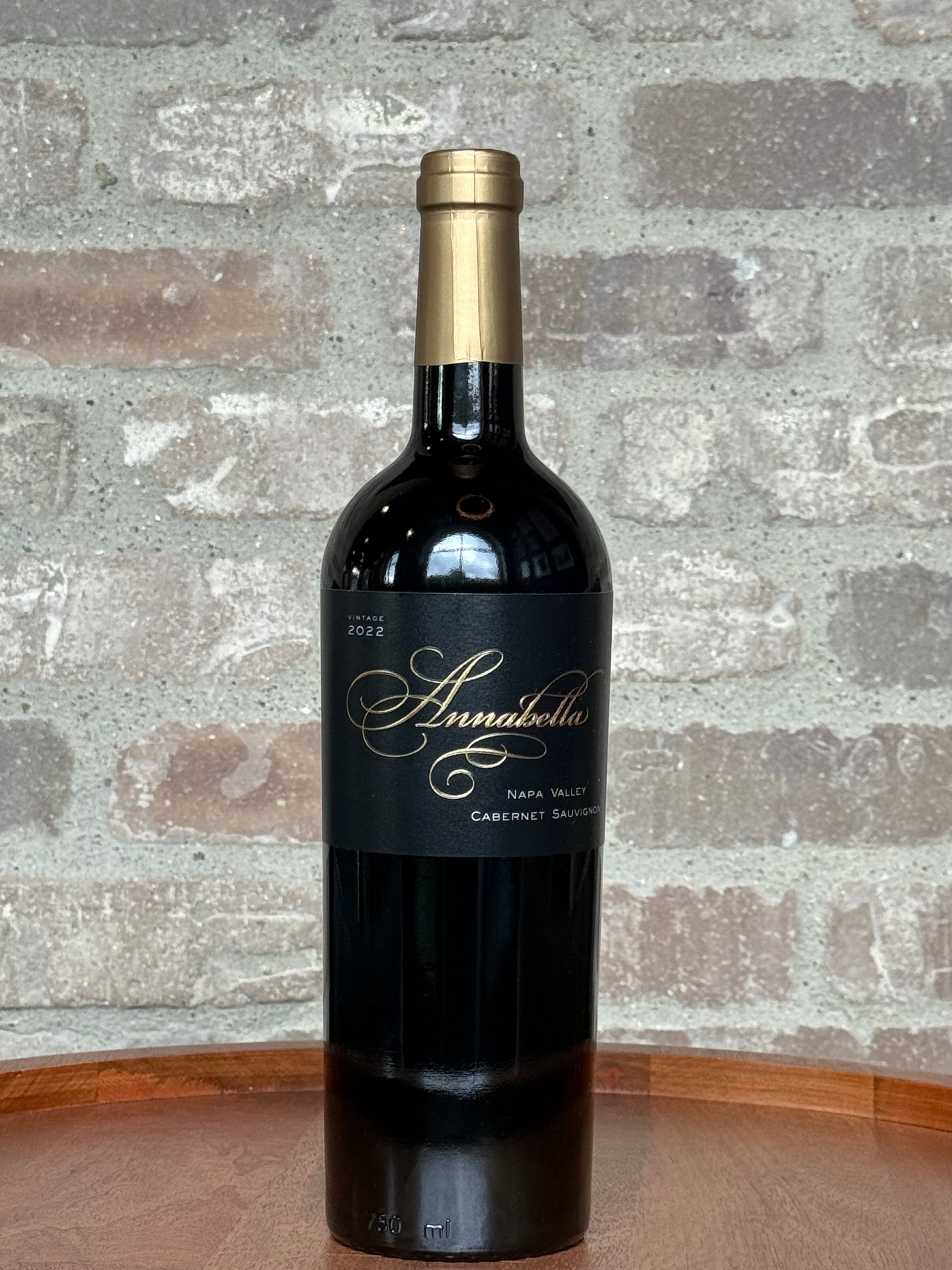 Wine bottle with 'Annabella' label on a wooden surface and brick wall background