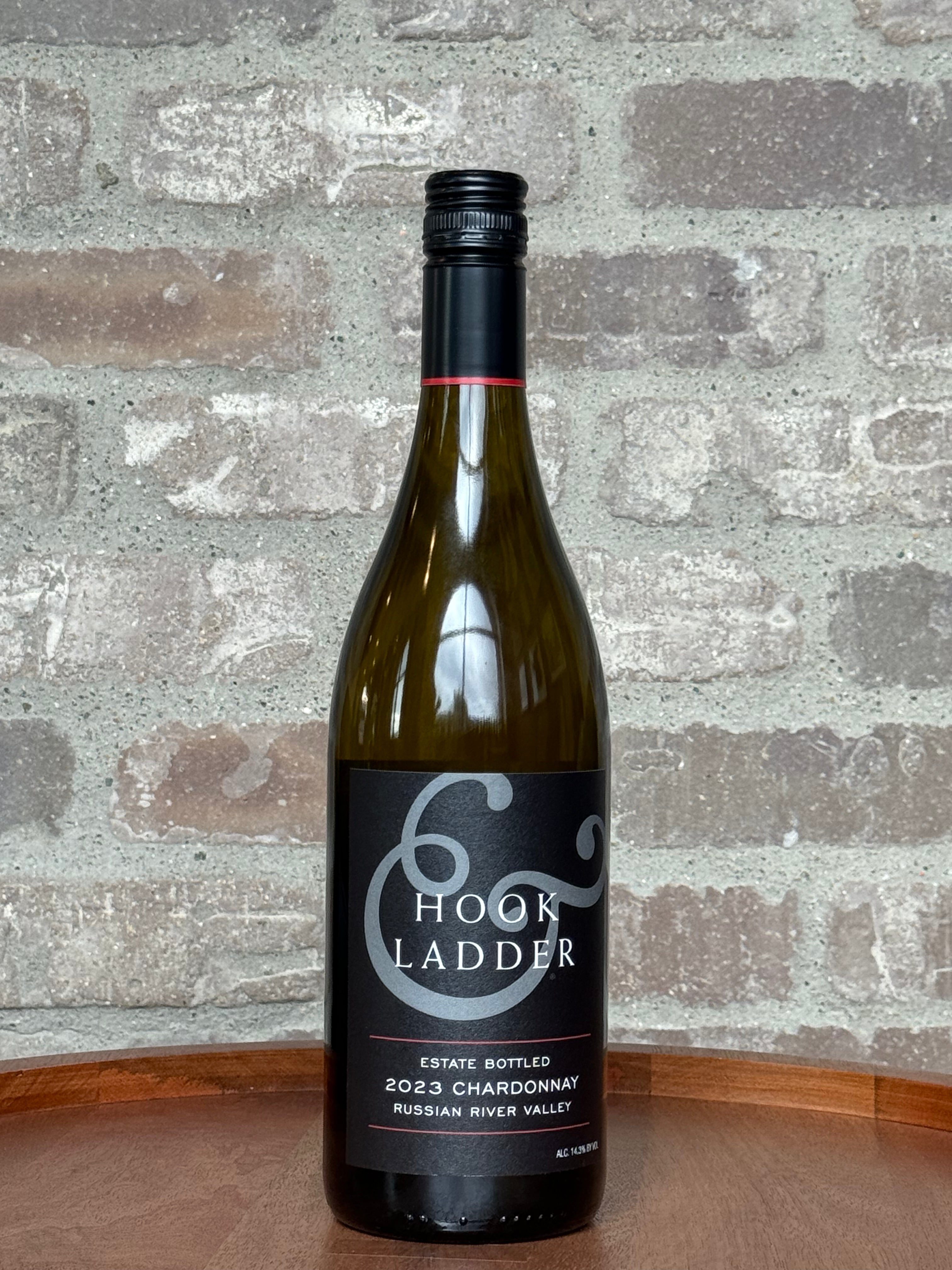 Wine bottle labeled 'Hook and Ladder' on a wooden surface with a brick wall background