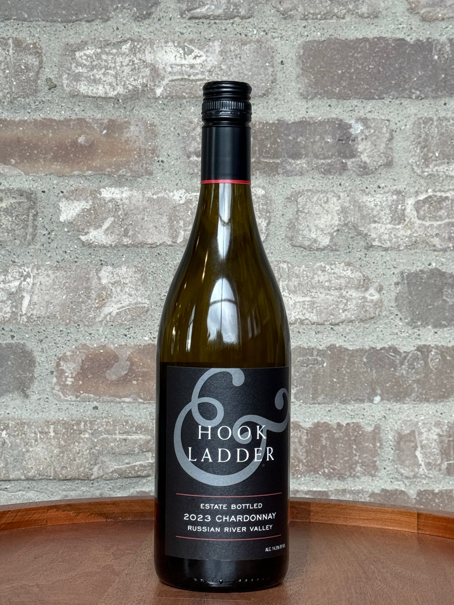 Wine bottle labeled 'Hook and Ladder' on a wooden surface with a brick wall background